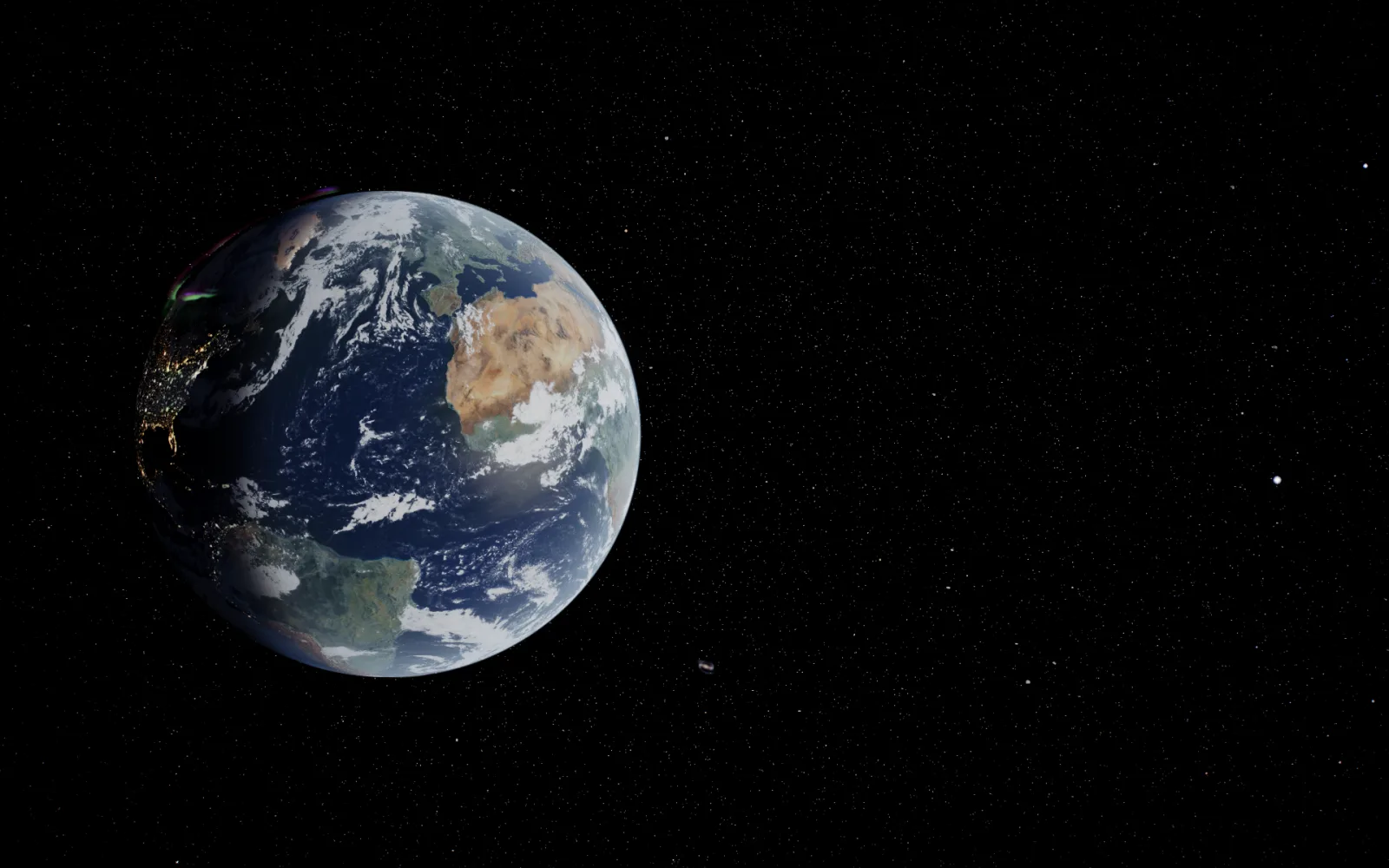 The Earth on the left of a desktop, its night side lit by cities